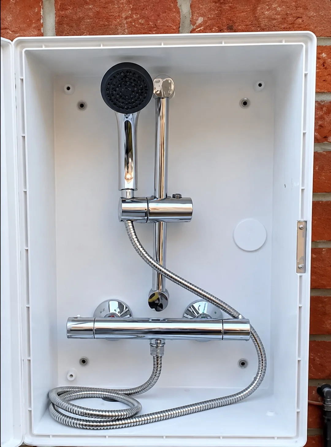 Close-up of a dog-shower mixer valve, handset and hose fitted inside a wall-mounted enclosure