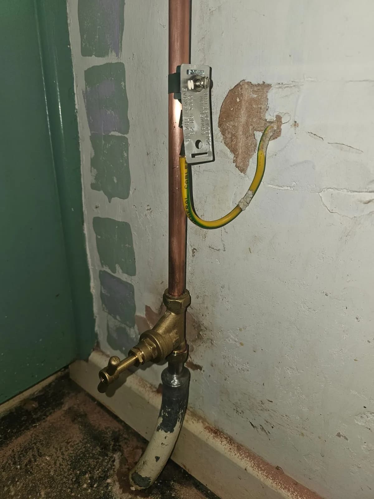 Stop tap, copper pipework and earth bonding detail on an internal wall